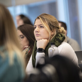 Student sitting in a lecture with her chin resting on her hand
