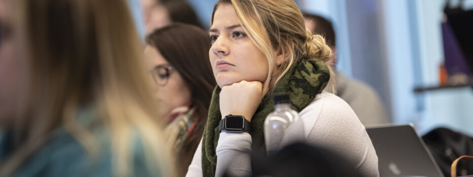 Student sitting in a lecture with her chin resting on her hand