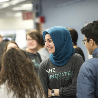 Student smiling while talking with a group of other students