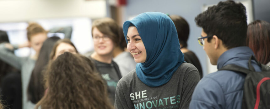 Student smiling while talking with a group of other students