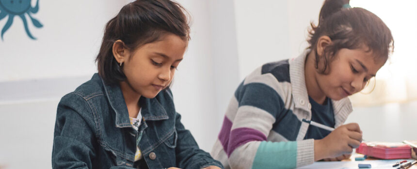 Two young students writing on worksheets