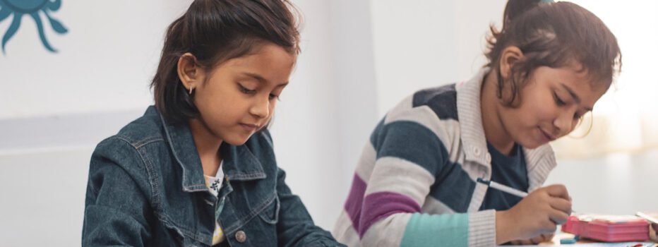 Two young students writing on worksheets