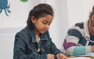 Two young students writing on worksheets