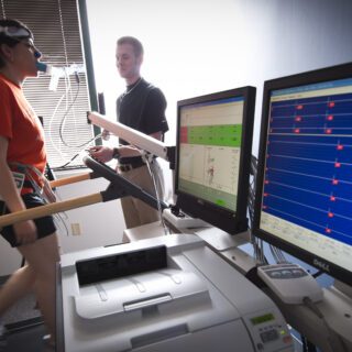 A student walking on a treadmill hooked up to a machine measuring her rate rate and breathing