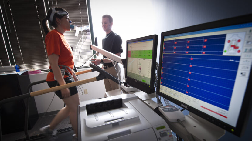 A student walking on a treadmill hooked up to a machine measuring her rate rate and breathing