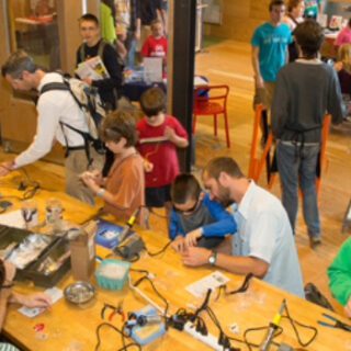 Children, youth, and adults gathered at tables building things for a community event