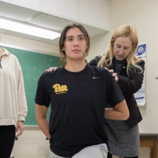 Students receiving training on stretching and physical therapy in a classroom lab with the teacher