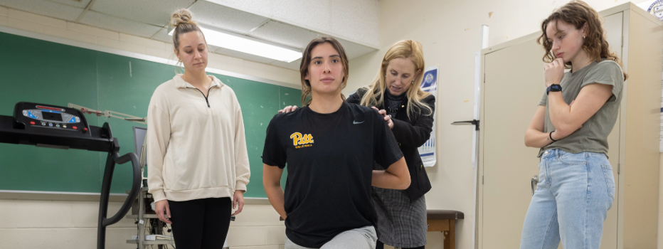 Students receiving training on stretching and physical therapy in a classroom lab with the teacher