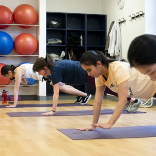 Four people doing planks in a group fitness room