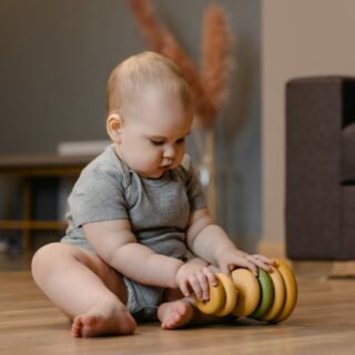 Baby sitting on the floor with a ring stacking toy