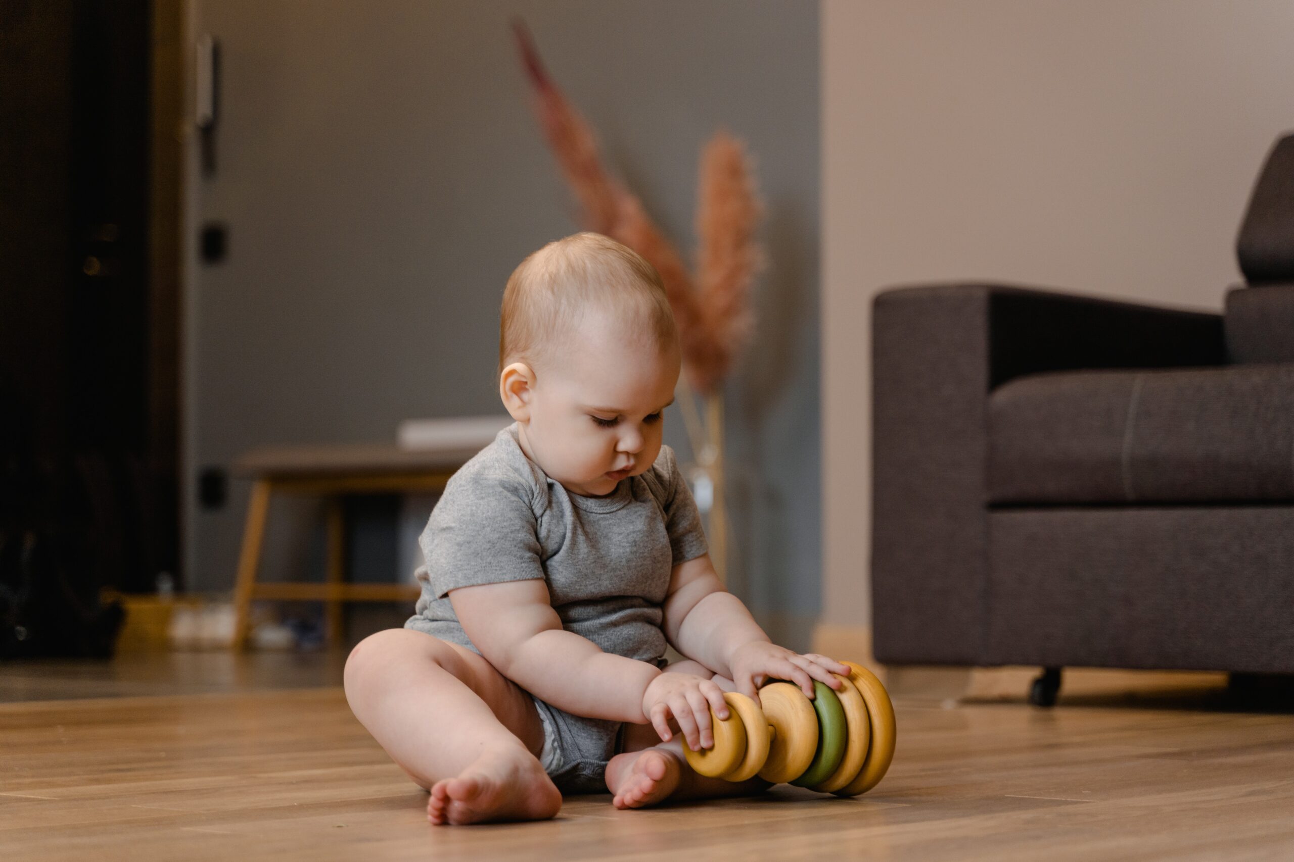 Baby sitting on the floor with a ring stacking toy