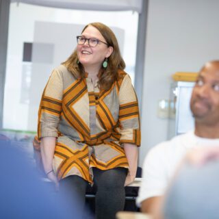 A teacher/aspiring school leader sitting on a desk and staring up at the ceiling while smiling