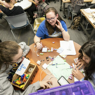 Three students work on a circuitry project in a makerspace classroom