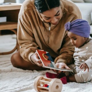 Mother and baby sitting on the floor reading a book