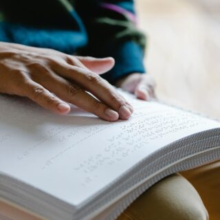Hand reading braille in a book