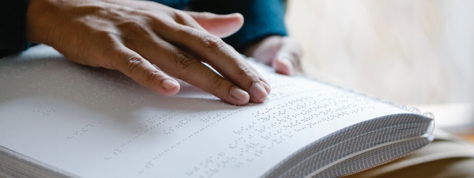 Hand reading braille in a book