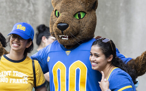 Pitt's mascot, Roc, poses with two students