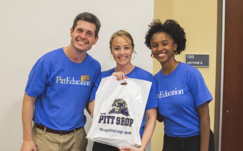 Two students smiling with a staff member at orientation