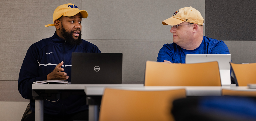 EdD students, two men, talking in the classroom