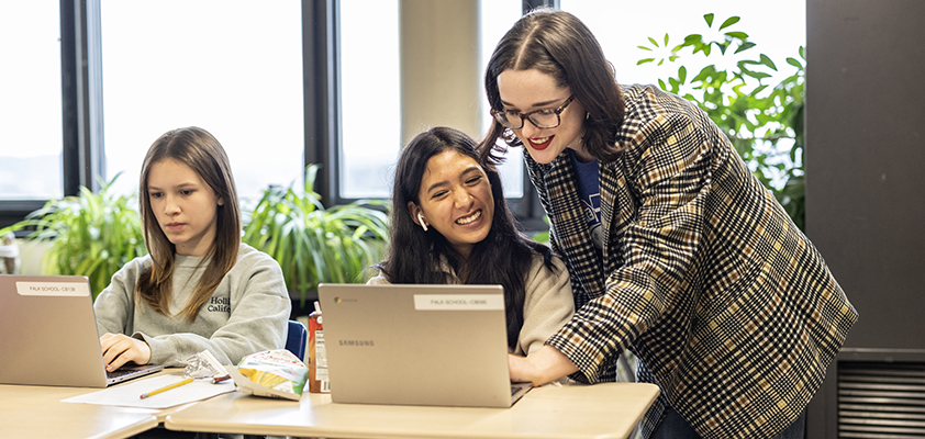 Student-teacher helps a young student on a laptop