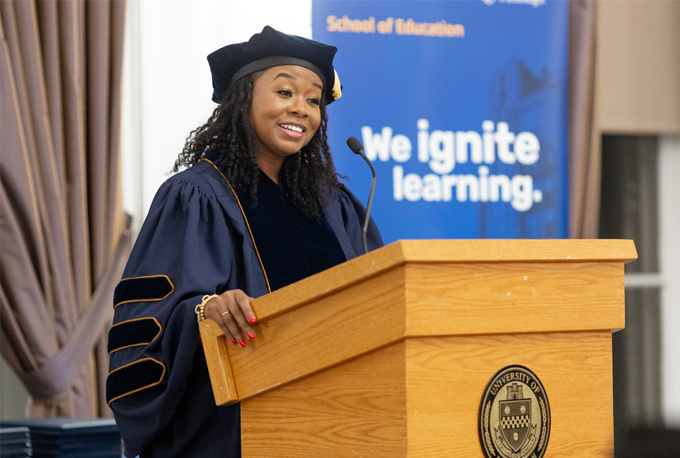 Pitt graduate speaking at ceremony in front of podium