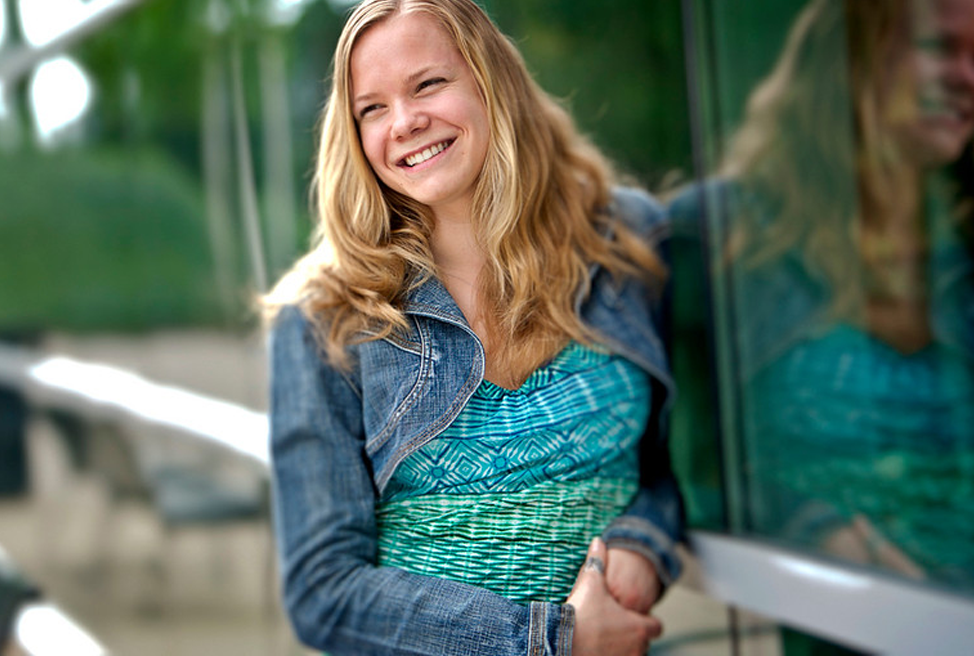 Alumna smiling in front of a glass wall