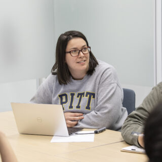 Students learning together in classroom, with girl in a Pitt sweatshirt in center of the room