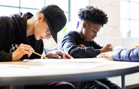 Two students together in a classroom looking over an assignment