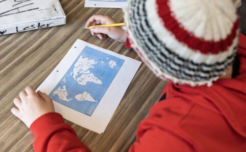 A student wearing a cap looking down at a map