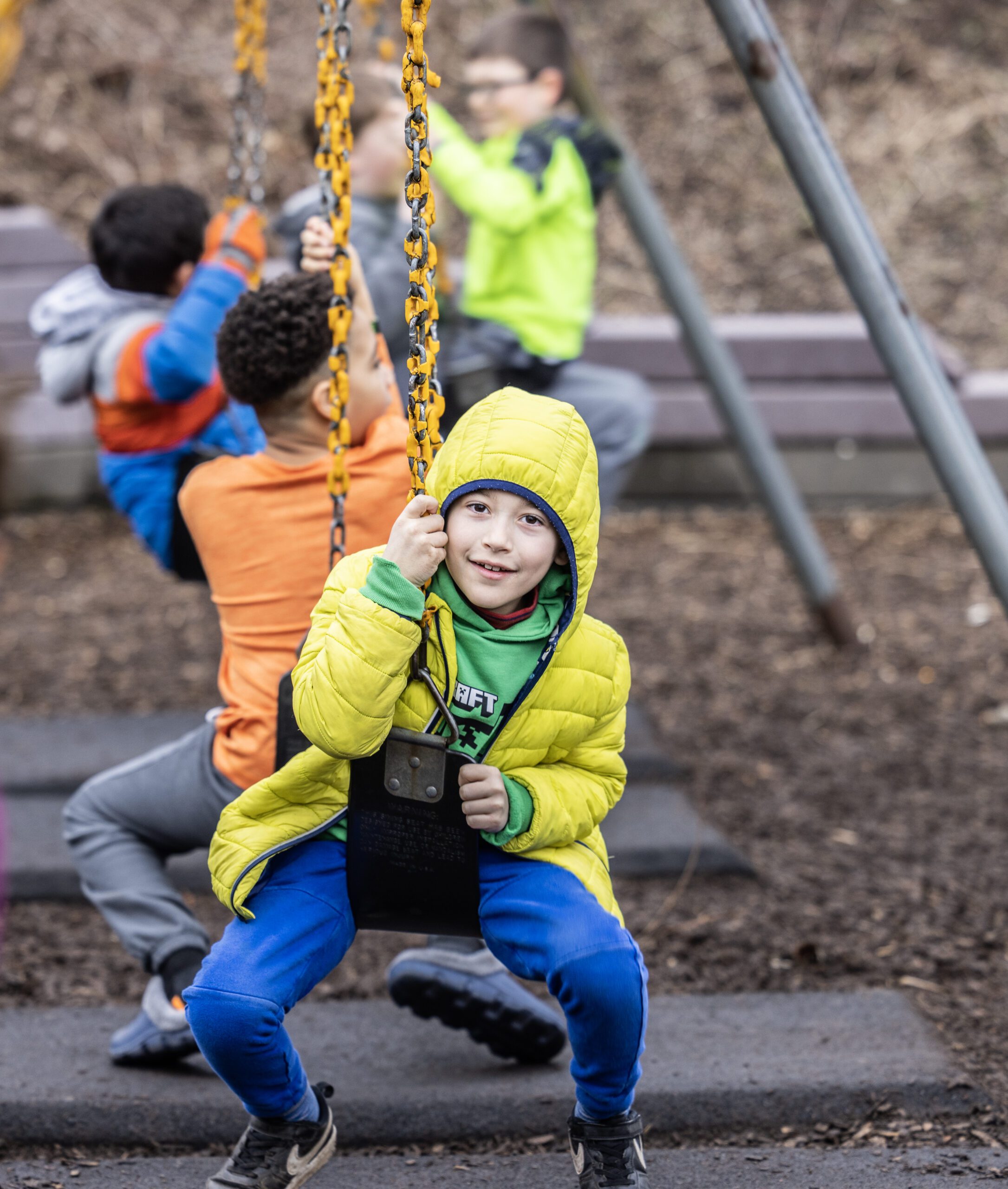 A young boy on a swing set smiling