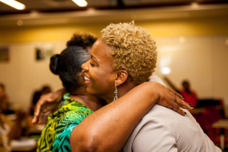 Two woman hugging each other at a community event