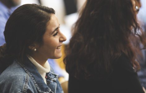 A girl smiling in a room with other people pursuing freedom-based work