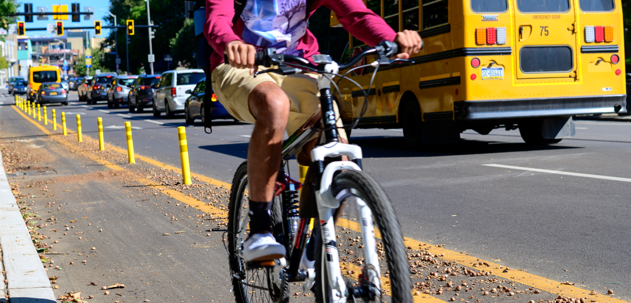 A child riding a bike to school with a school bus in the background