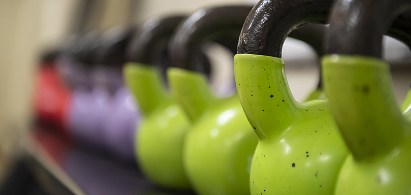 Close-up of green, purple, and red kettlebells in a row