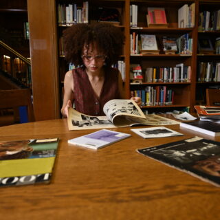A student reading multiple books and research materials in a library
