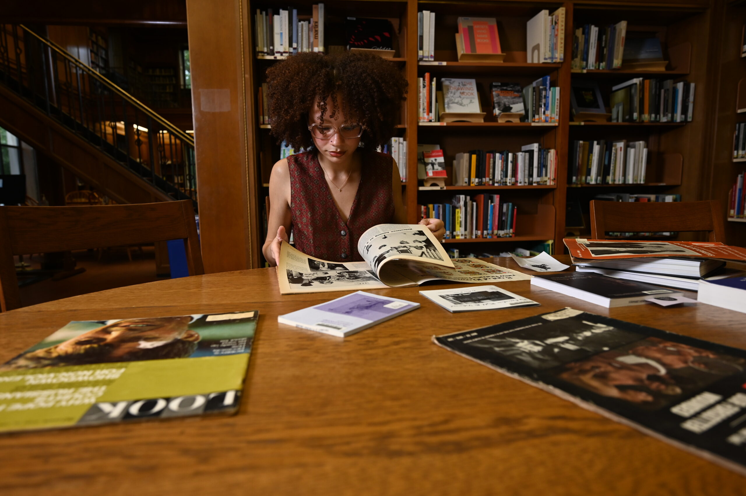 A student reading multiple books and research materials in a library