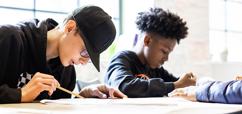 Two middle school students writing at a desk