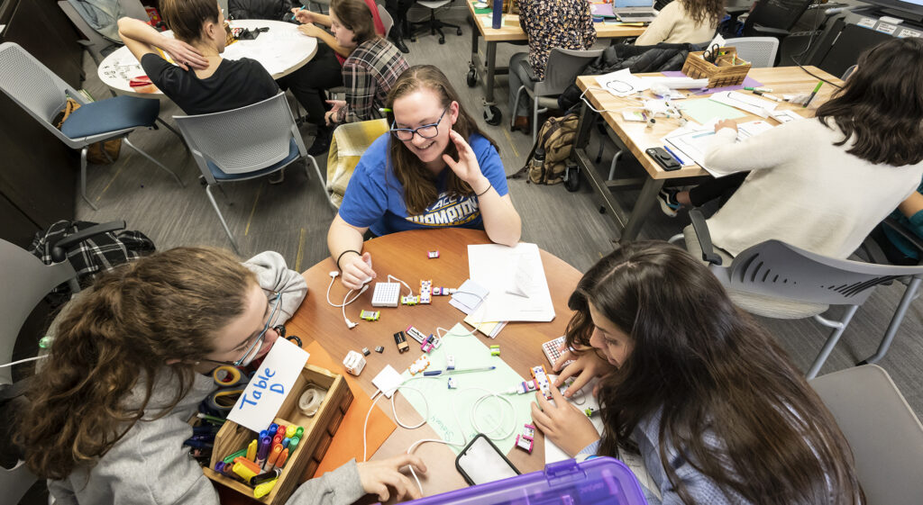 Three students working on a circuitry project at a table