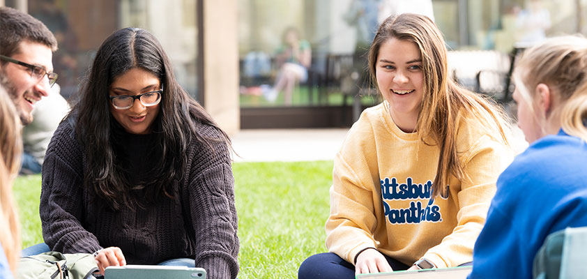 A group of transfer students sitting on the lawn on campus