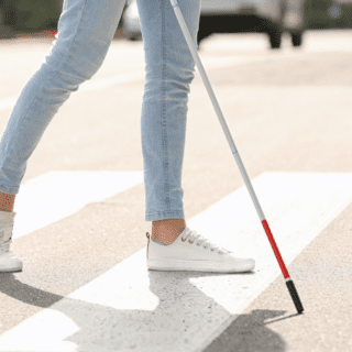 Close-up of a person crossing a street with a white cane