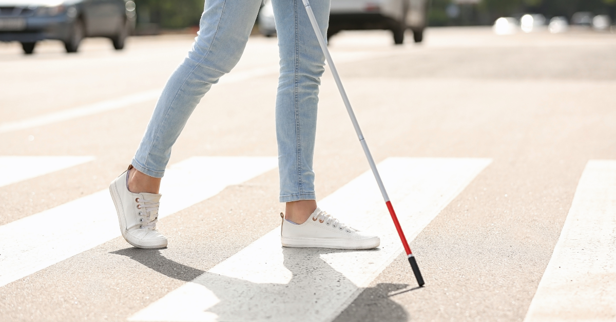 Close-up of a person crossing a street with a white cane