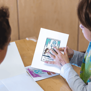 A group of young children gathered in a circle are discussing a drawing