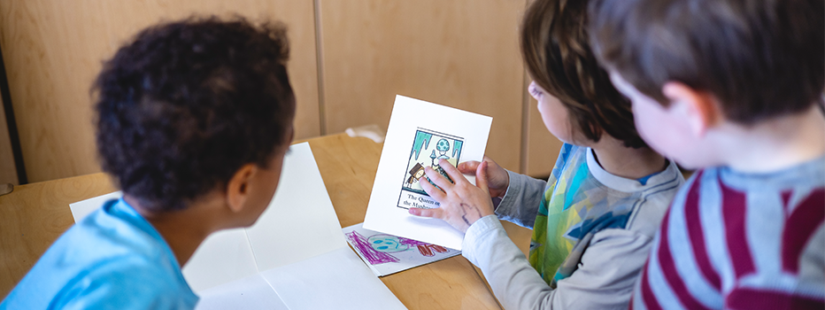 A group of young children gathered in a circle are discussing a drawing