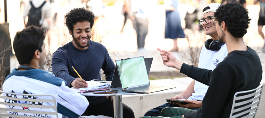 A group of college students at a table outside talking and laughing